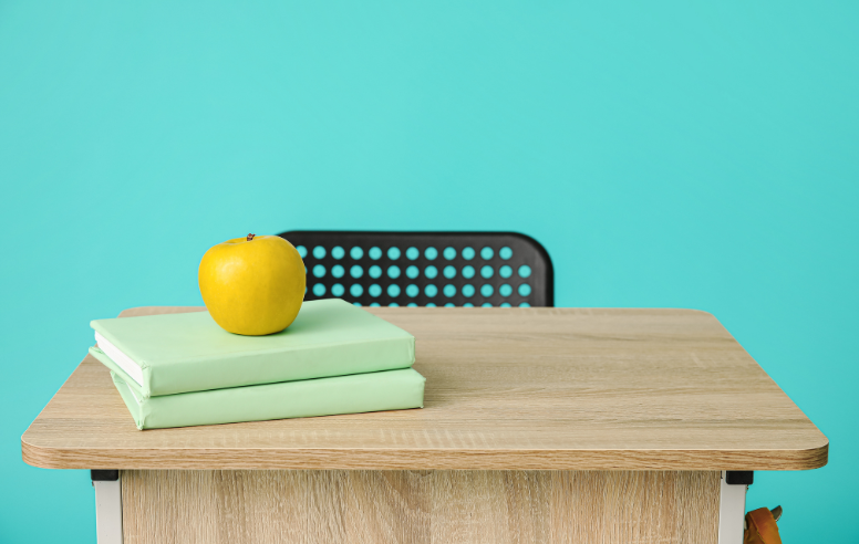 Empty desk with books and an apple.