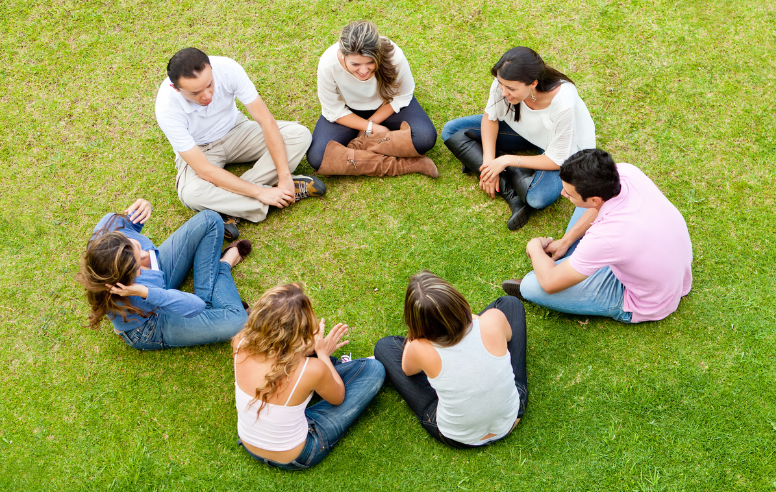Group circle outside on the grass.
